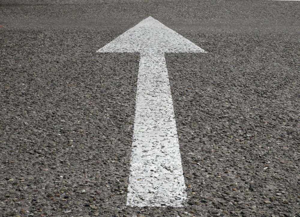 A white arrow on the ground with gravel