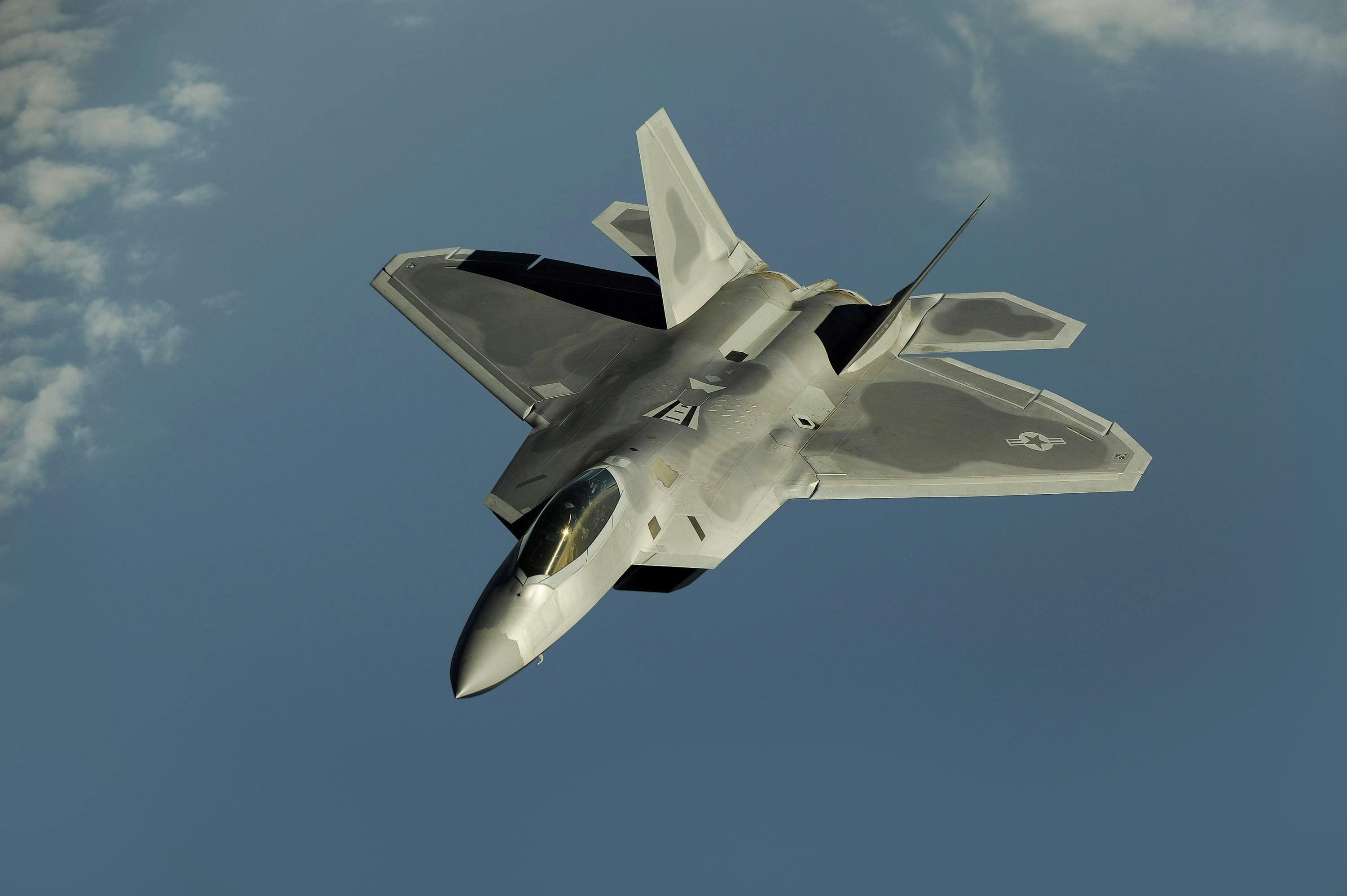 A fighter jet flying through the air with its landing gear down.